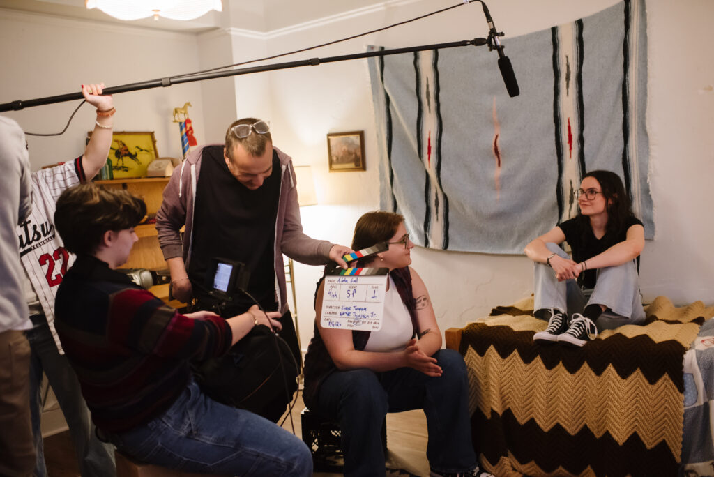 Behind the scenes shot of filmmaking and acting students filming a scene of a film.