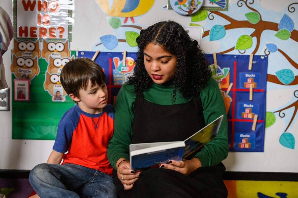 Student teacher from the Education program reads to a young boy at the Children's School