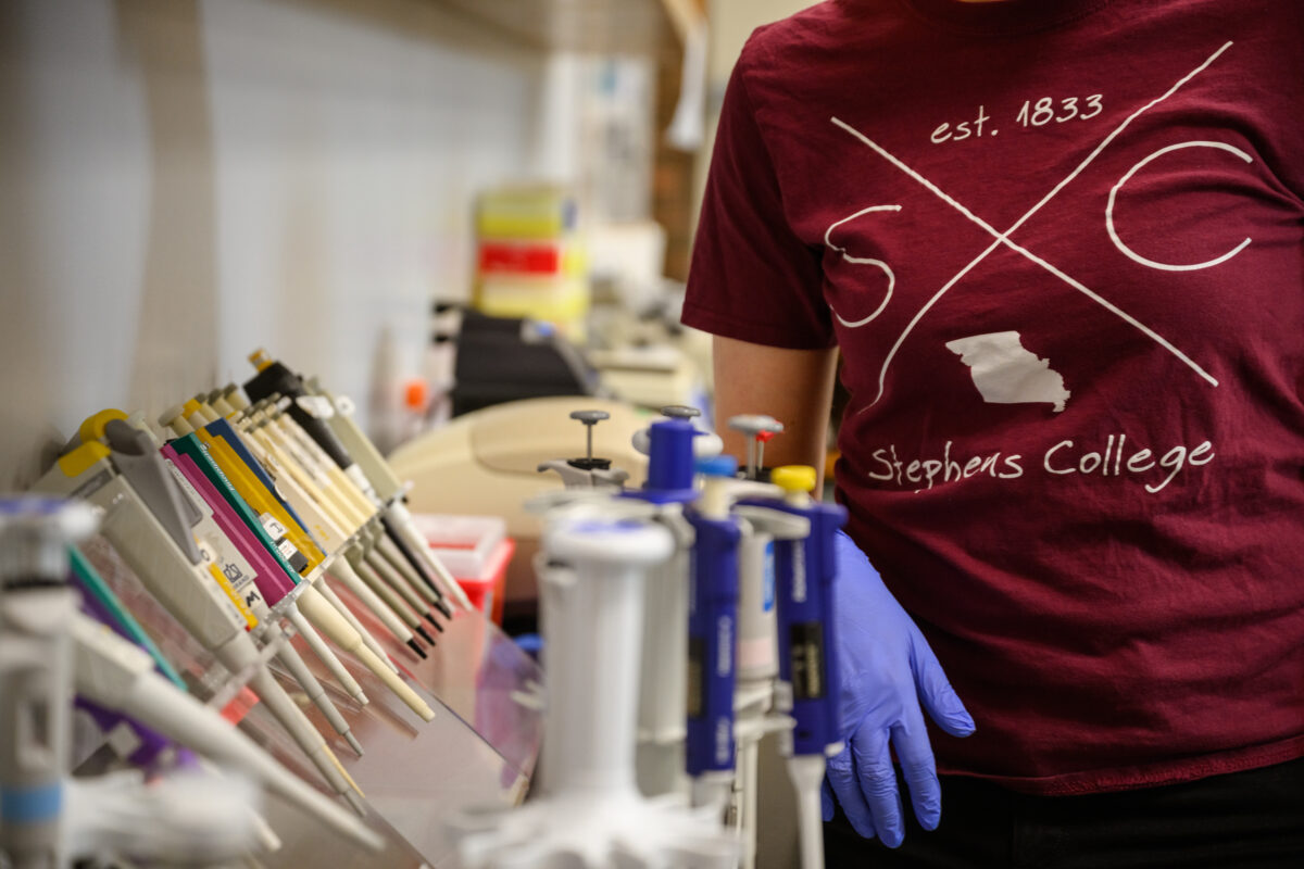 Biology student wears gloves while working in a lab