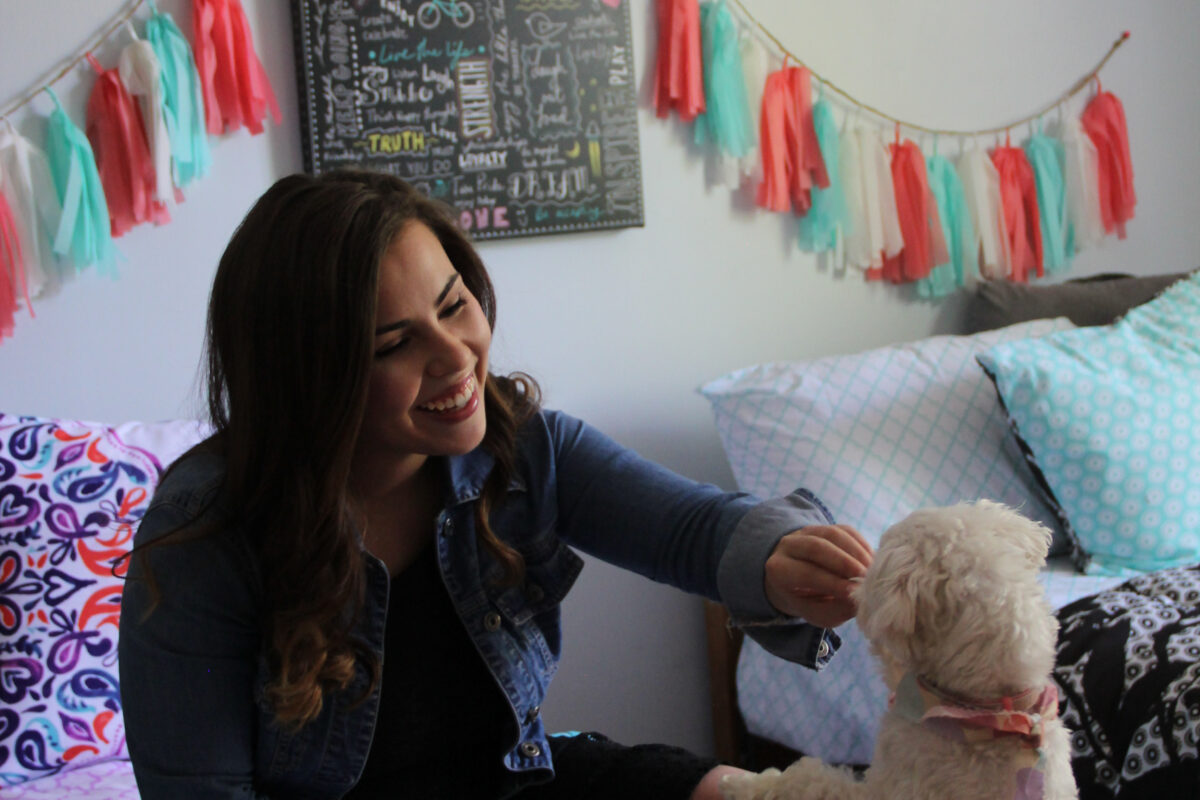 Student playing with her dog in her dorm room.