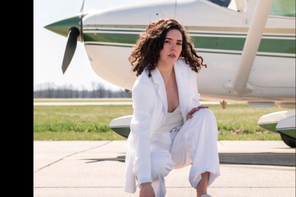 Woman poses in front of an airplane on a Stephens Life magazine cover.