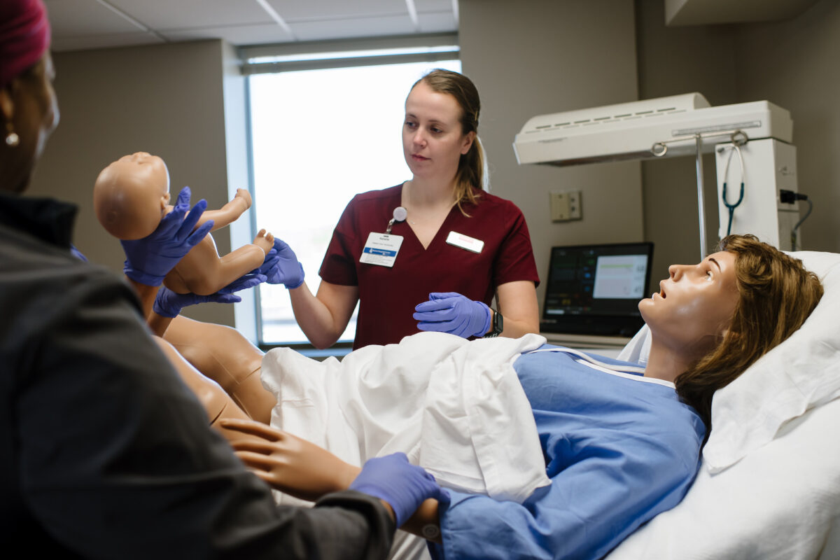 Nursing students practice in the sim lab with an OB 