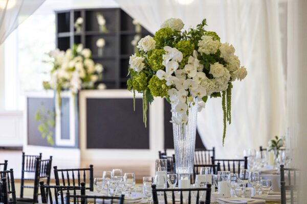 A wedding event space with floral centerpiece and black and white bar in the background