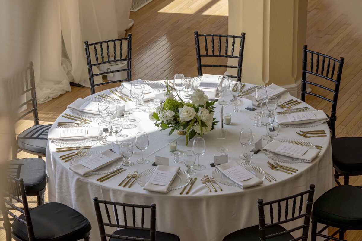 A fully set table with centerpiece, place settings and menus