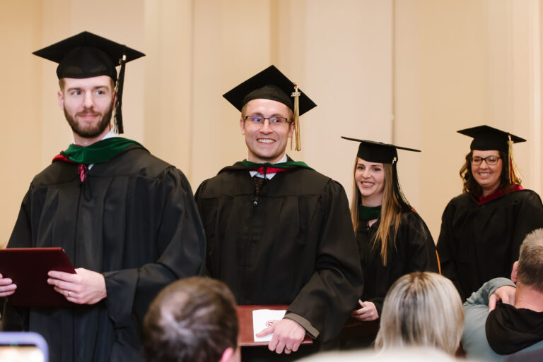 Graduates smiling while in line to receive their diplomas.