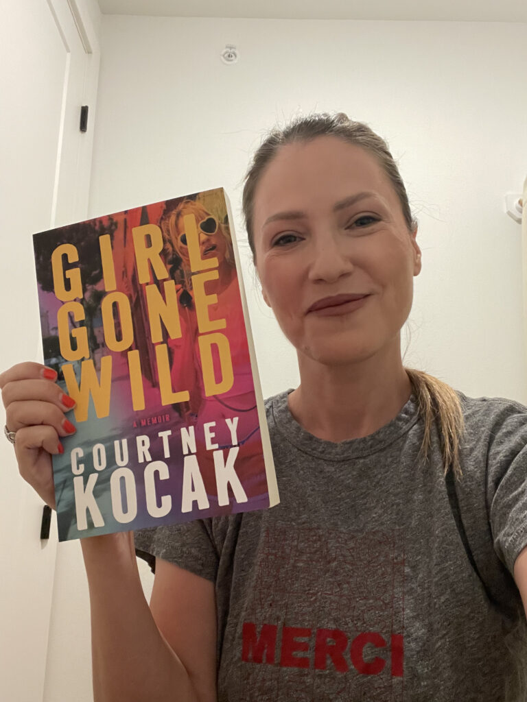 Courtney Kocak smiling with Girl Gone Wild Book